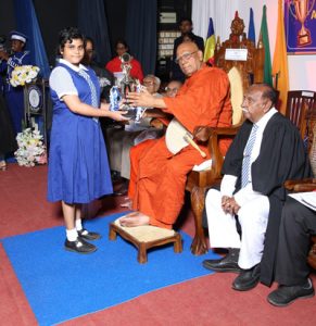 A student receiving a trophy from Most Ven Omalpe Sobitha Thera